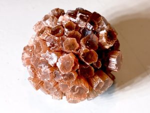 Cristaux d'aragonite maclés en forme sphérique. Teinte transparente nuancée d'orange d'oxyde de fer.